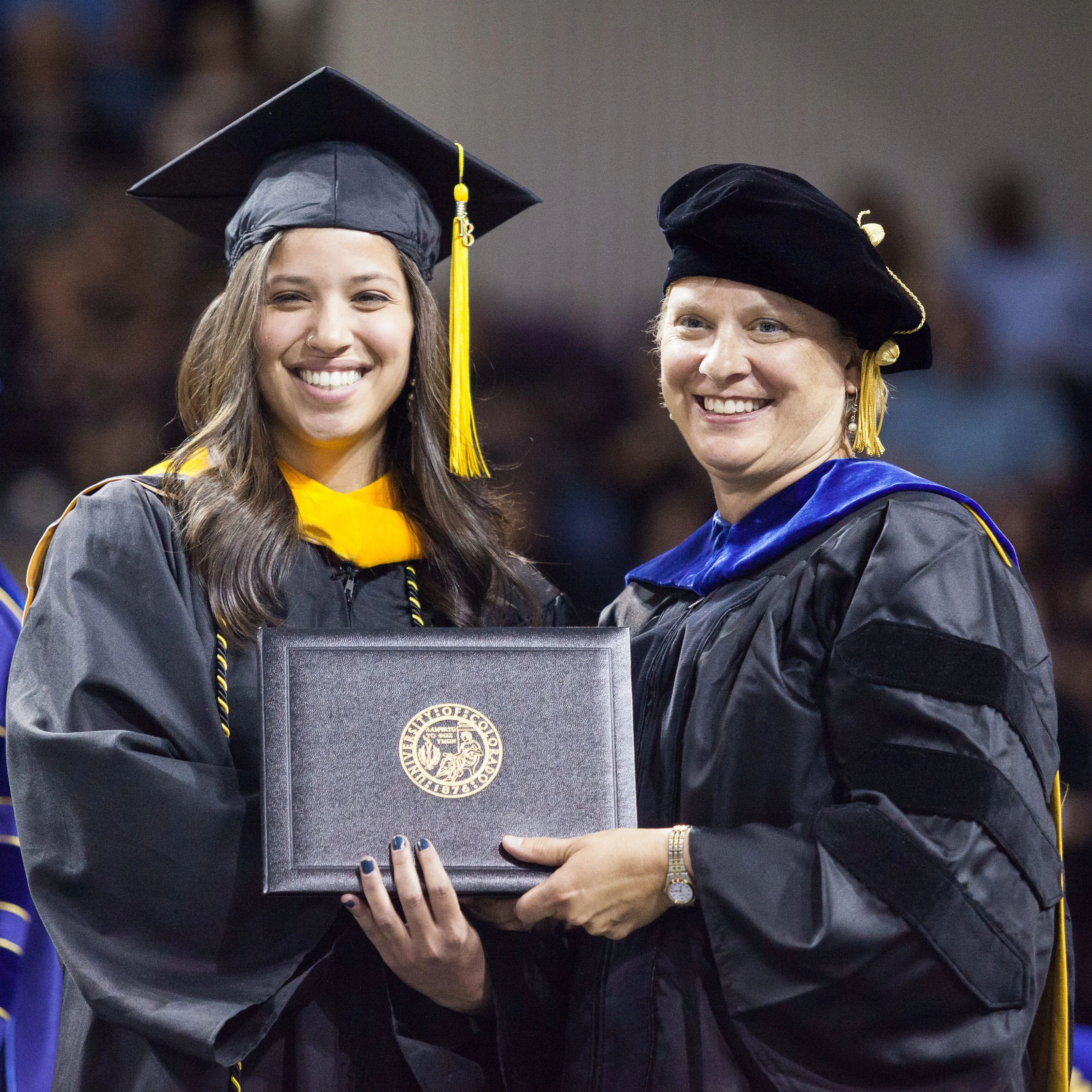 student and faculty holding diploma